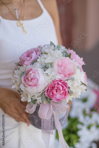 Girl holding beautiful mix pink and white peonies flowers in grey round box in womans hands for flowers store. Floral shop concept.