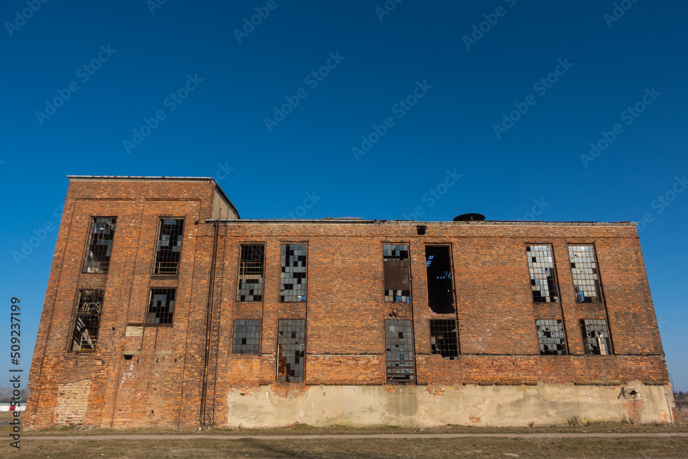 Ruins of an abandoned industrial plant. Brick walls against the background of the blue sky. Photo taken on a sunny day.