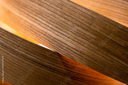 A close-up of a room lamp made of veneer strips. The object is illuminated by atmospheric light