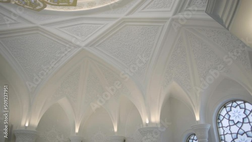  Beautiful view of the fashionable building.Scene.Large white walls and high ceilings made of marble and painted on them and hanging yellow small lamps on the walls.