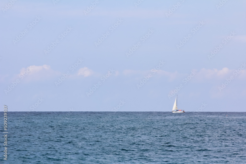 Minimalistic seascape with a strip of sea, sky and a lonely sailboat