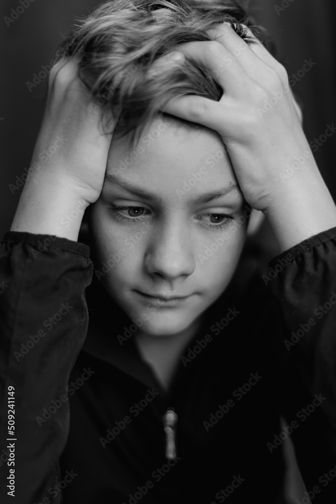 Black and white portrait of teenage boy on dark background. Low key close up shot of a young teen boy. Black and white photography. Selective focus Black and white portrait of teenage boy on dark background. Low key close up shot of a young teen boy. Black and white photography. Selective focus