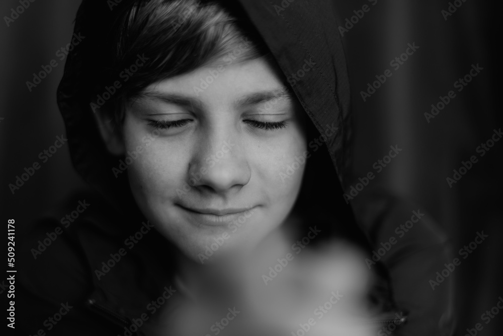 Black and white portrait of teenage boy on dark background. Low key close up shot of a young teen boy. Black and white photography. Selective focus Black and white portrait of teenage boy on dark background. Low key close up shot of a young teen boy. Black and white photography. Selective focus