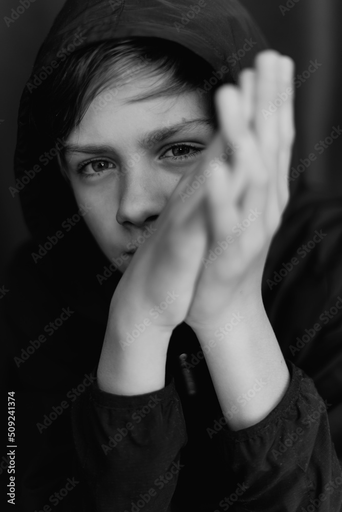 Black and white portrait of teenage boy on dark background. Low key close up shot of a young teen boy. Black and white photography. Selective focus Black and white portrait of teenage boy on dark background. Low key close up shot of a young teen boy. Black and white photography. Selective focus