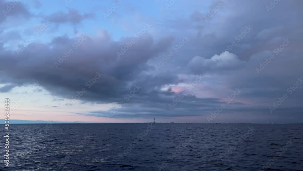 Dramatic sunset in the waters of the Gulf of Finland, view from the boat, strong wind and waves, storm clouds over the water, the sun sets over the horizon Dramatic sunset in the waters of the Gulf of Finland, view from the boat, strong wind and waves, storm clouds over the water, the sun sets over the horizon