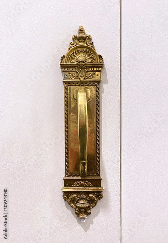 Antique poignée de porte en métal dorée. Enluminures et détails gravés sur une poignée de porte en laiton ancienne.   photo