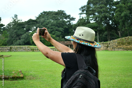 Mujer latina tomando un fotografias mientras visita las ruinas de Iximche en Guatemala. photo