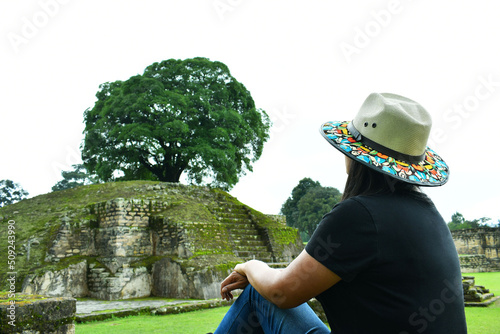 Mujer viajera sentada, observando uno de los templos en las Ruinas de Iximche en Guatemala. photo