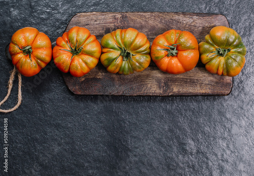 A group of Costoluto big tomatoes on a wooden background, rustic concept, space for text photo