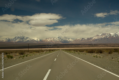 Traveling along the asphalt highway across the arid desert and into the Andes cordillera, under a beautiful blue sky with clouds. photo