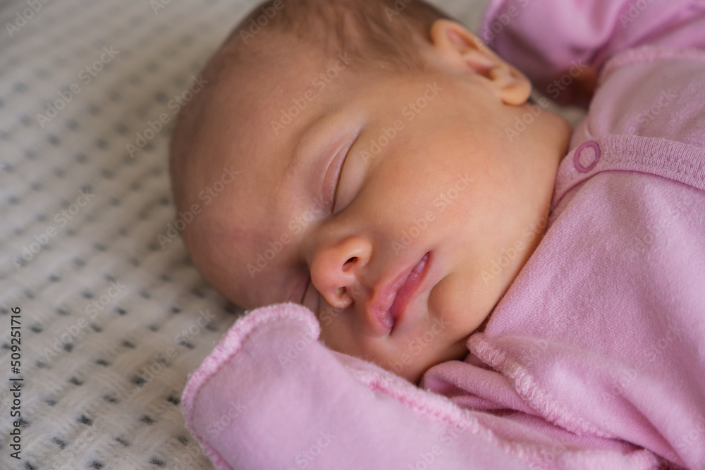 cute little newborn baby girl peacefully sleeps in the nursery on a white cotton bed cute little newborn baby girl peacefully sleeps in the nursery on a white cotton bed