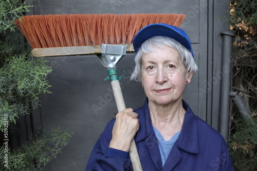 Obraz na plátně Senior female street cleaner with broom