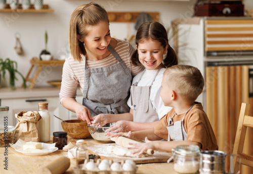 Happy woman and cute children cooking together in kitchen