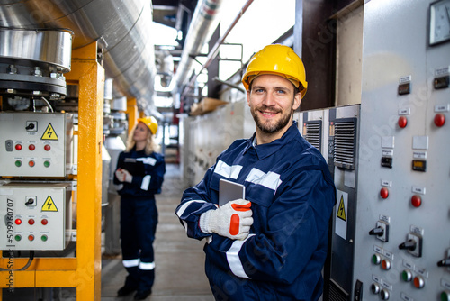 Portrait of an industrial electric engineer standing by power supply inside oil refinery. photo