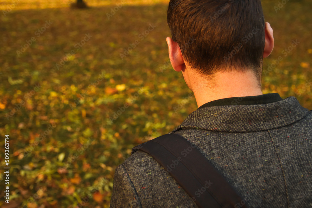 Defocus closeup portrait of a young handsome man sad looking down in the park, the woods in autumn. Portrait on the nature of the park, the woods, on the street. Sad. Back view. Out of focus Defocus closeup portrait of a young handsome man sad looking down in the park, the woods in autumn. Portrait on the nature of the park, the woods, on the street. Sad. Back view. Out of focus
