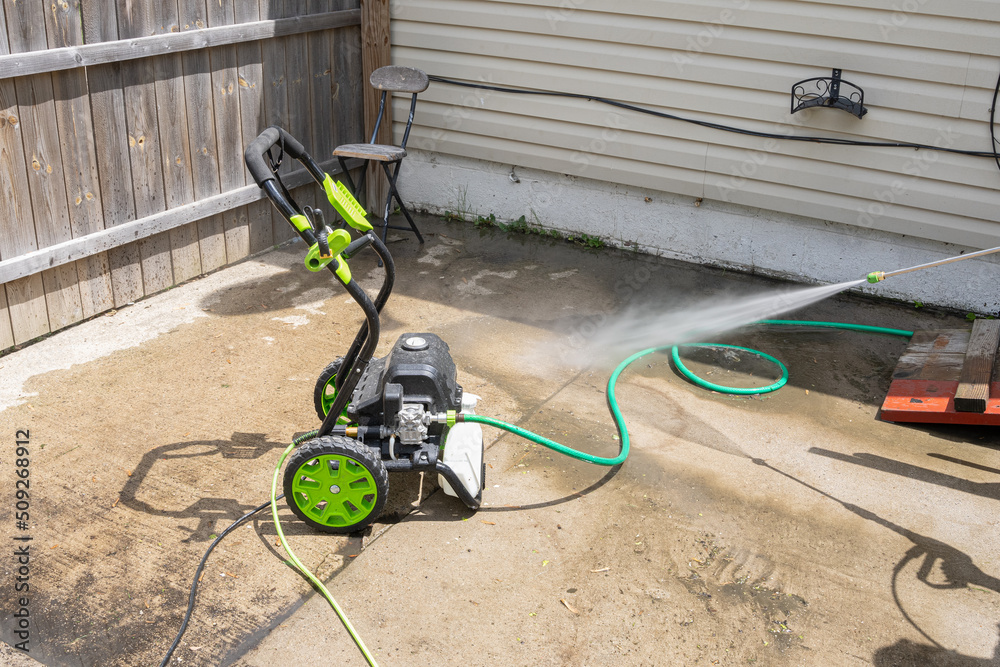 pressure washer is spraying high pressure water to clean dirt and algae from the patio foto de