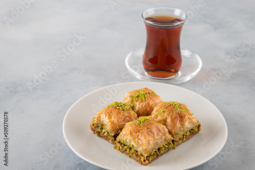 Pistachio baklava on a white plate with Turkish tea	