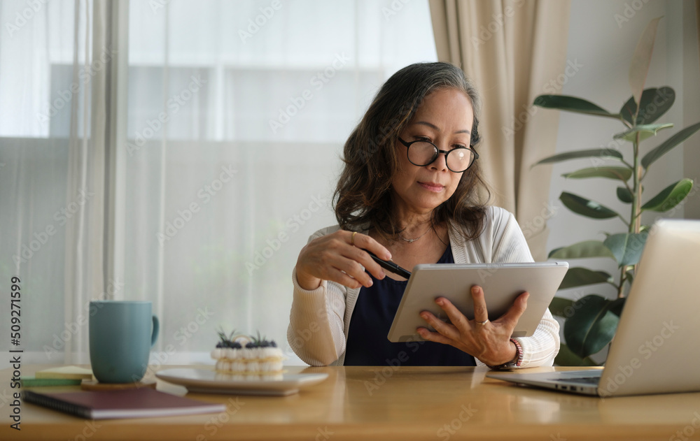 Middle aged woman working, spending time in social media internet while sitting in comfortable home. Middle aged woman working, spending time in social media internet while sitting in comfortable home.