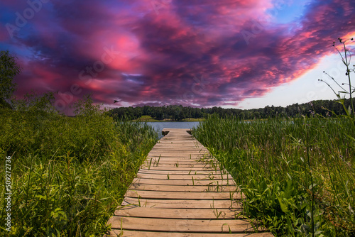 a brown wooden dock over the rippling blue waters of Lake Acworth surrounded by lush green trees and blue with powerful clouds at sunset at Cauble Park in in Acworth Georgia USA photo