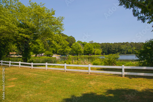 a gorgeous summer landscape at Lake Acworth with rippling blue lake water surrounded by lush green grass and trees with a white wooden fence and a gorgeous clear blue sky at Cauble Park in Acworth photo