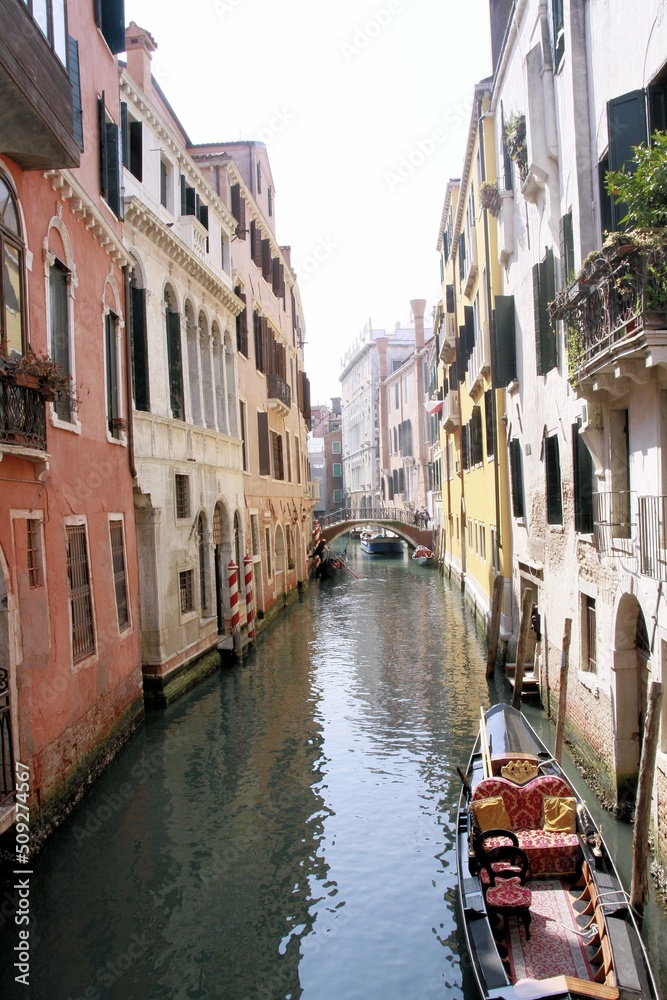 Góndola estacionada en canal de agua que une con un puente grupo de casas antiguas adosadas en Venecia