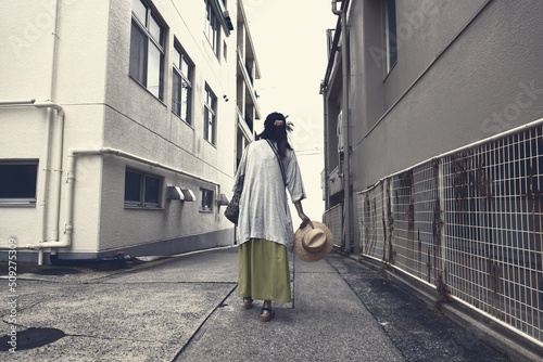 舗装された道路のある小さな路地を歩いている女性 © M&M Factory