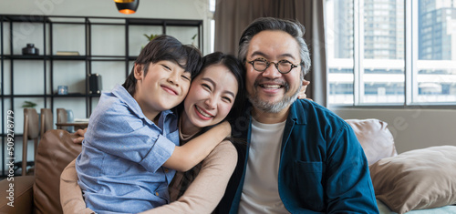 Portrait of happy Asian family spending time together on sofa in living room. family and home concept. © saksit