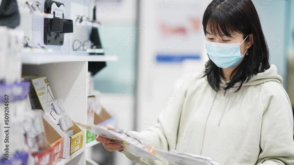 young chinese woman with mask chooses product in supermarket
young chinese woman with mask chooses product in supermarket