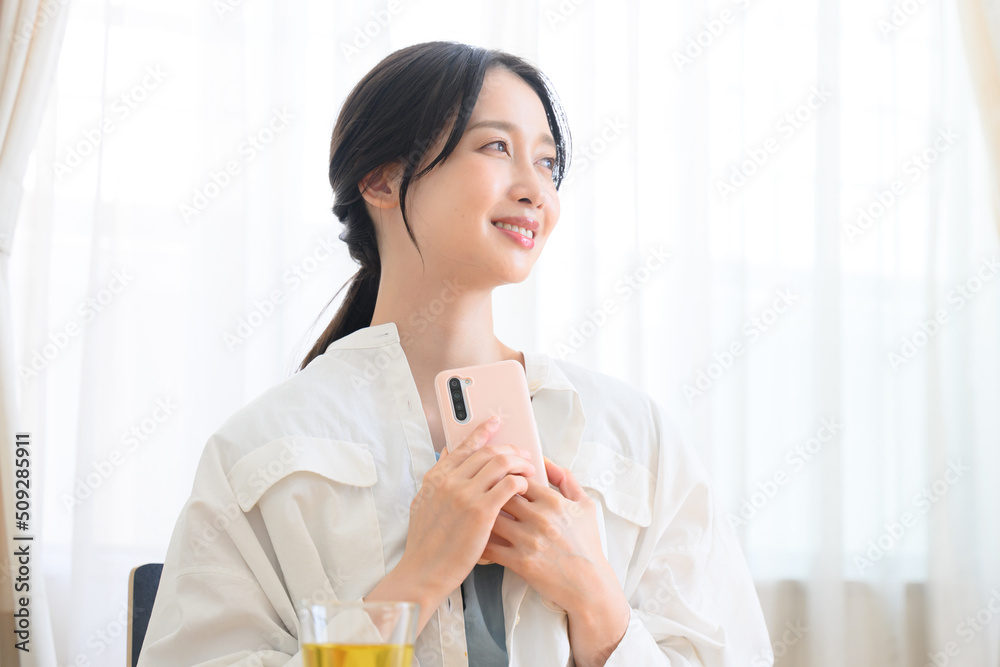 スマホで返事を楽しみにしている女性 スマホで返事を楽しみにしている女性