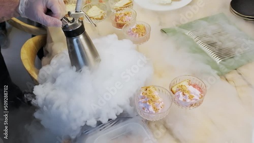 Cooking in restaurant. Cooker at work. Proffessional chef in gloves cooks dessert with dry ice. Chef pours water into bowl with dry ice. Slow motion.