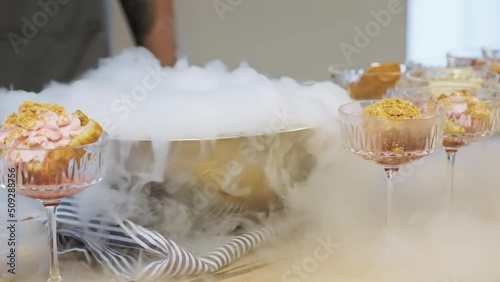Cooking in restaurant. Cooker at work. Proffessional chef in gloves cooks dessert with dry ice. Chef pours water into bowl with dry ice. Slow motion.