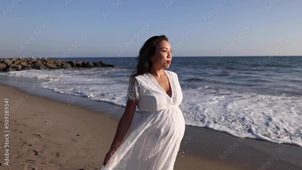 Attractive pregnant Asian woman enjoys a walk on the beach. Attractive pregnant Asian woman enjoys a walk on the beach.