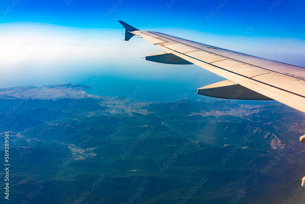 View from the airplane window at a beautiful blue clear sky and the airplane wing View from the airplane window at a beautiful blue clear sky and the airplane wing