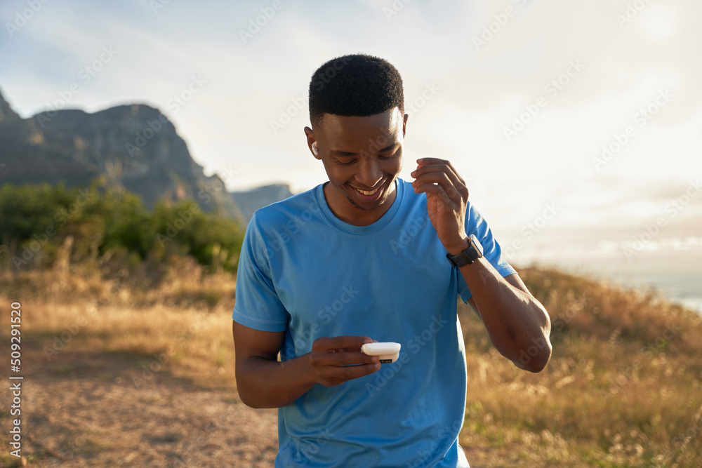 Fototapeta premium Black young Adult male putting in his earphones about to go for his morning mountain run. Exercising outdoors