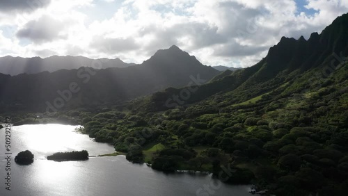 Dolly aerial shot of an ancient fishpond and coastal mountain ridge on the island of O'ahu, Hawaii. 4K photo