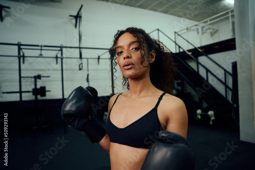 African American female boxer training at the gym with boxing gloves on. Mixed race female holding boxing gloves in air. High quality photo © StratfordProductions