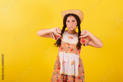 Girl wearing traditional orange clothes for festa junina. Thumb down, disapproval. bad. photo