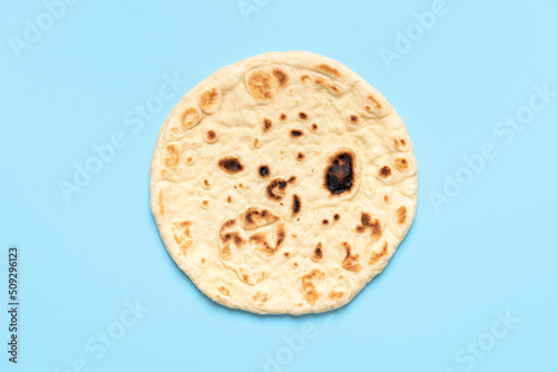 Naan bread isolated on a blue background. Indian flatbread above view photo