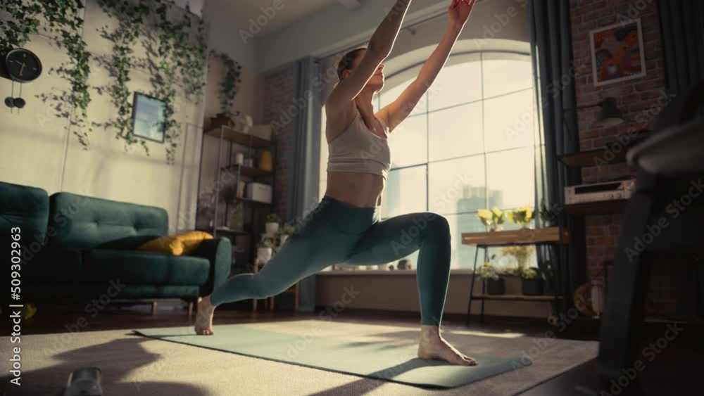 Young Beautiful Female Exercising, Stretching and Practising Yoga in the Morning in Her Bright Sunny Loft Apartment. Healthy Lifestyle, Fitness, Wellbeing and Mindfulness Concept. Young Beautiful Female Exercising, Stretching and Practising Yoga in the Morning in Her Bright Sunny Loft Apartment. Healthy Lifestyle, Fitness, Wellbeing and Mindfulness Concept.