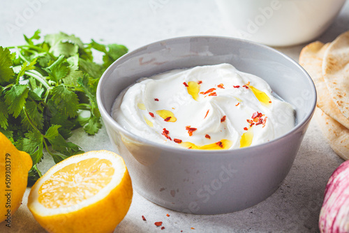 Whipped feta cheese dip with garlic and lemon in gray bowl. Greek cuisine concept.