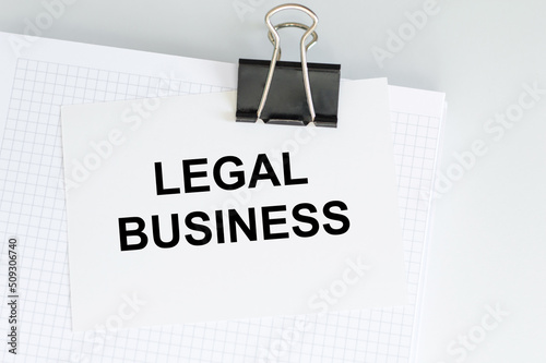 LEGAL business text on a card clip to a white sheet of notepad on the table, business concept