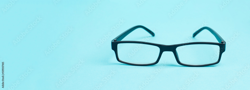 Glasses with a black frame on a blue background, copy space for text
