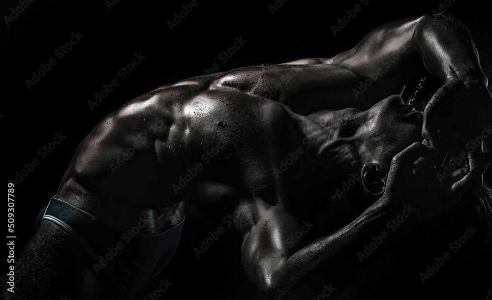 Sexy young handsome naked man on dark background. Seductive gay.