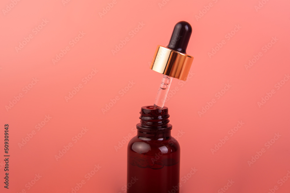 glass brown bottle with pipette with essential oil on a pink background top view. Aromatic cosmetic product for skin and hair care Moisturizing beauty product with organic glass brown bottle with pipette with essential oil on a pink background top view. Aromatic cosmetic product for skin and hair care Moisturizing beauty product with organic