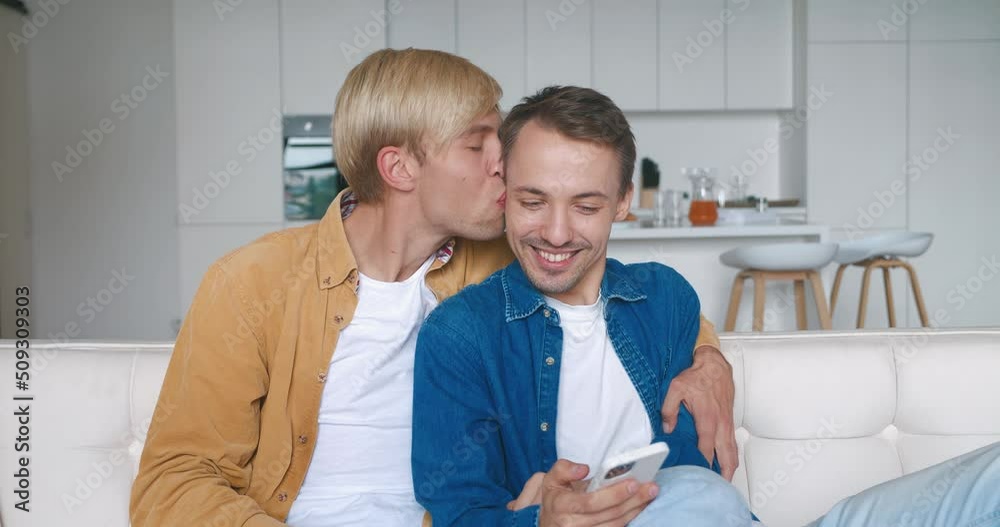 Surprised two males gay couple winners hold smartphone read good news amazed by mobile online bet bid game win at home while sitting on sofa. Surprised two males gay couple winners hold smartphone read good news amazed by mobile online bet bid game win at home while sitting on sofa.