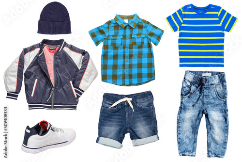 Collage set of little boys spring clothes isolated on a white background. Denim trousers or pants, short jeans, sneaker, a rain jacket, shirts and a cap for child boy. Children's summer fashion.