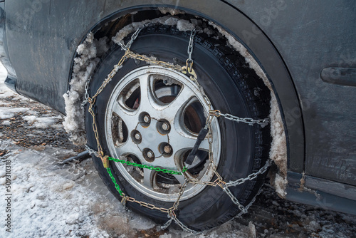 Close-up of snow chains on a car wheel in winter. The concept of safety on snowy roads.