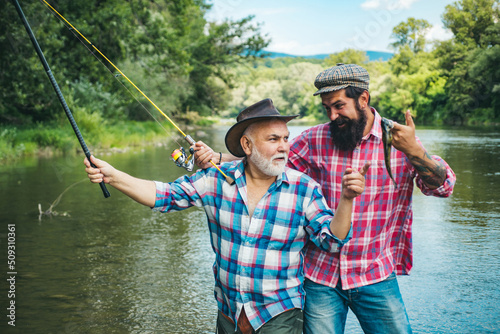 Mature senior man with friend fishing. Summer vacation. Happy cheerful people. Bearded men catching fish. Fisherman with fishing rod. Activity and hobby.