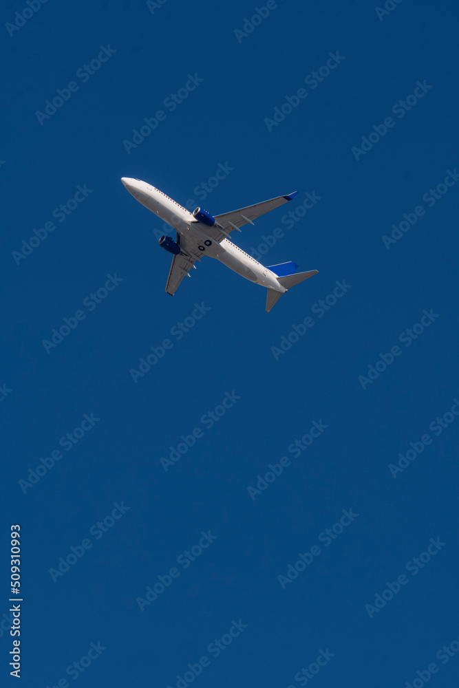 Aerial view of white airplane with blue tail, shot from below with selective focus. Aerial view of white airplane with blue tail, shot from below with selective focus.