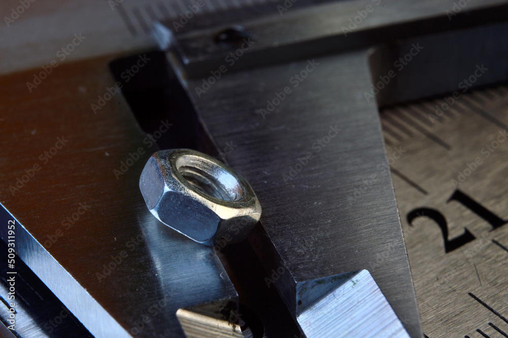 Accurate measuring tool caliper and metal ruler lie in place with nuts. close-up. Accurate measuring tool caliper and metal ruler lie in place with nuts. close-up.